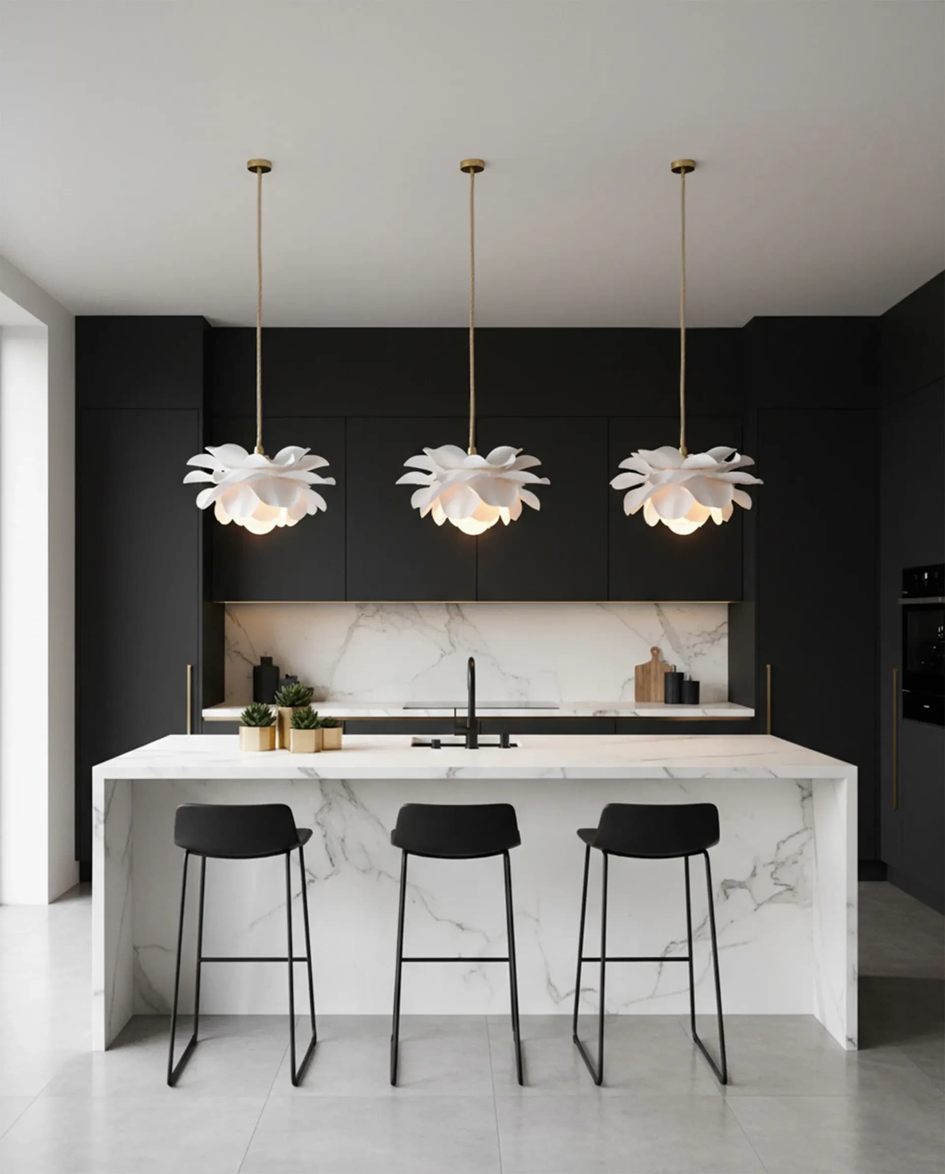 Three white flower pendant lights in a row above a marble kitchen island