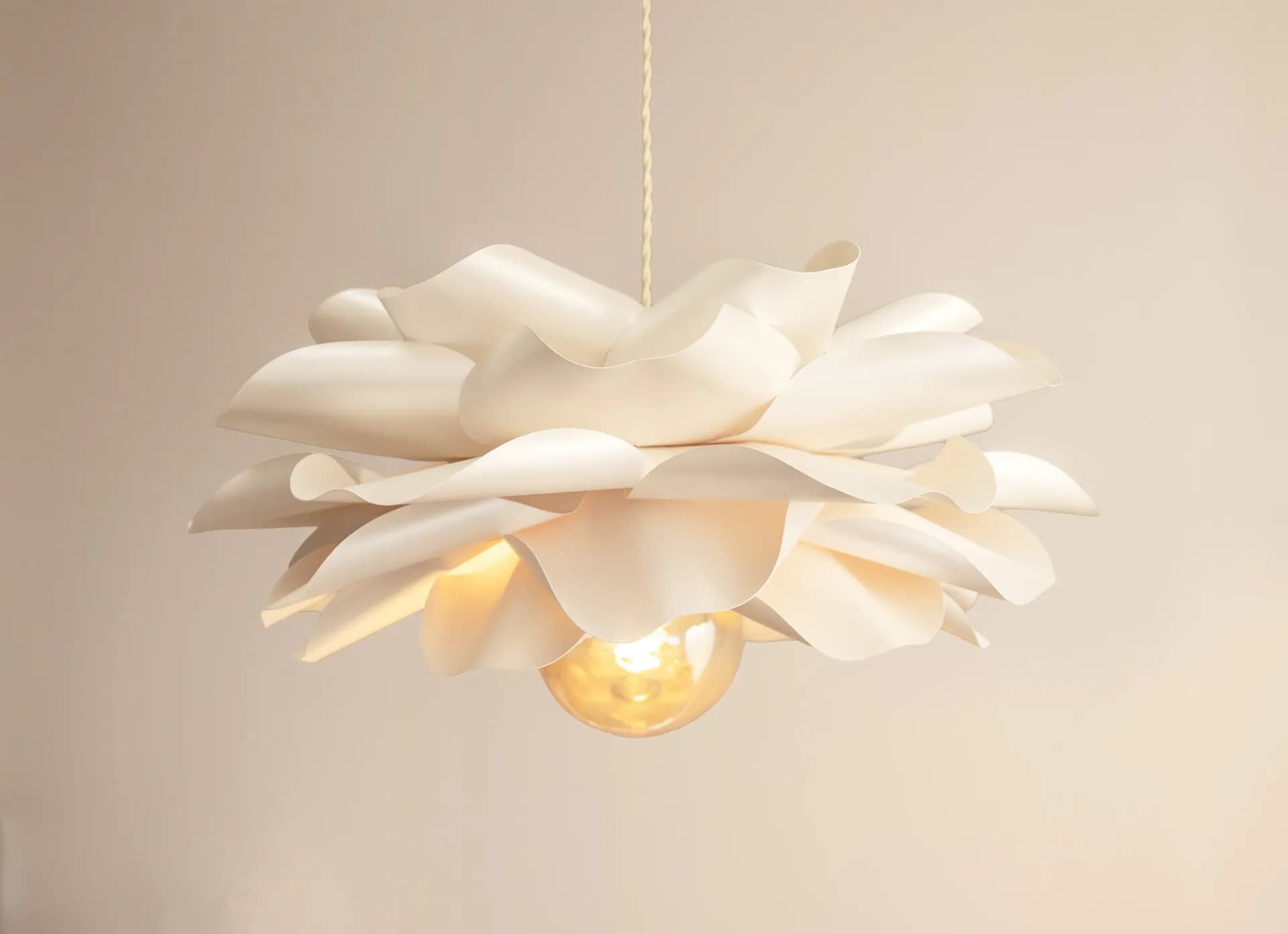 Ivory flower pendant lamp glowing against a warm evening wall